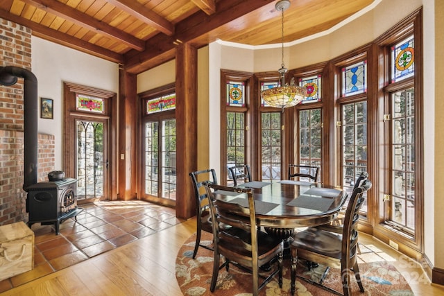 dining area featuring crown molding, beamed ceiling, a wood stove, tile floors, and wooden ceiling