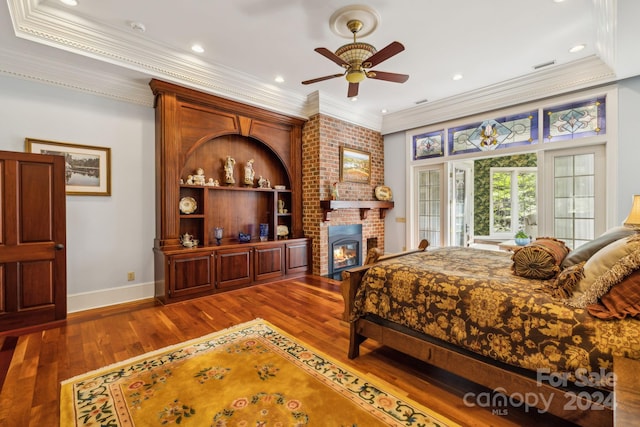 bedroom featuring ceiling fan, hardwood / wood-style floors, a fireplace, brick wall, and ornamental molding