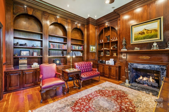 living area featuring built in features, ornamental molding, a fireplace, and hardwood / wood-style flooring