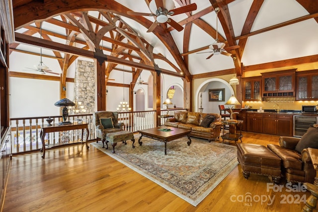 living room featuring wine cooler, ceiling fan, light hardwood / wood-style floors, high vaulted ceiling, and sink