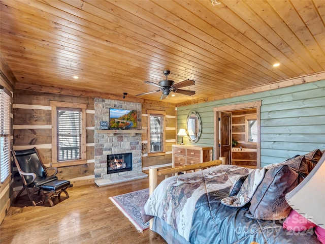 bedroom with a fireplace, wooden ceiling, wooden walls, hardwood / wood-style floors, and ceiling fan