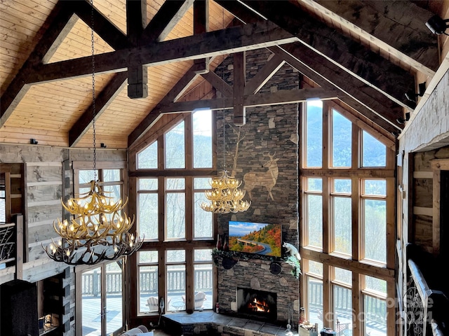 unfurnished living room with beam ceiling, a notable chandelier, high vaulted ceiling, and plenty of natural light