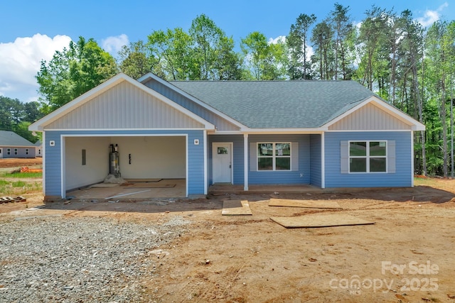 view of front of home featuring an attached garage, roof with shingles, and covered porch