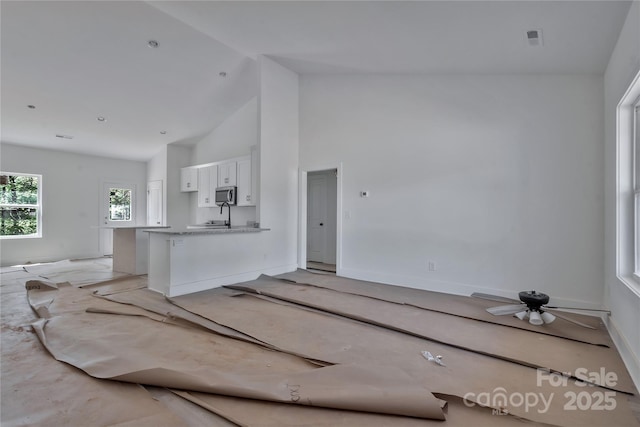 unfurnished living room featuring visible vents, high vaulted ceiling, and a sink