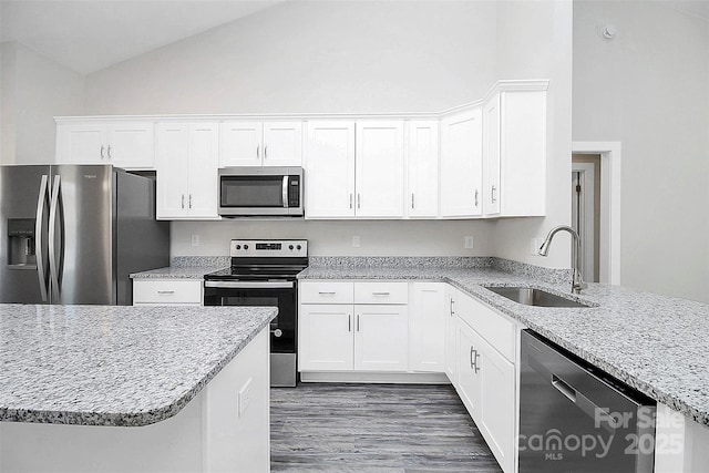 kitchen with high vaulted ceiling, a sink, white cabinets, appliances with stainless steel finishes, and light stone countertops