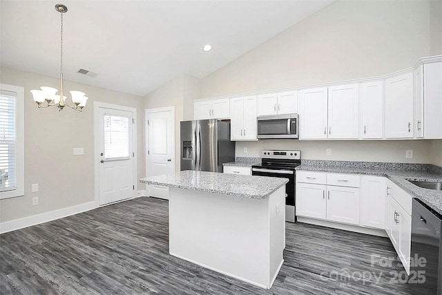 kitchen with a center island, appliances with stainless steel finishes, white cabinets, a notable chandelier, and visible vents