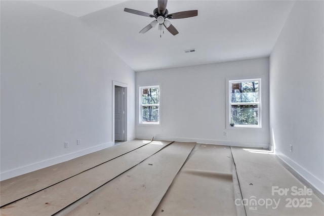 empty room with ceiling fan, vaulted ceiling, visible vents, and baseboards