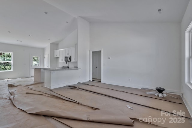 unfurnished living room featuring visible vents, high vaulted ceiling, and a sink