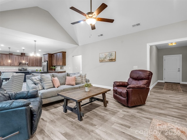 living room with high vaulted ceiling, ceiling fan, and light wood-type flooring