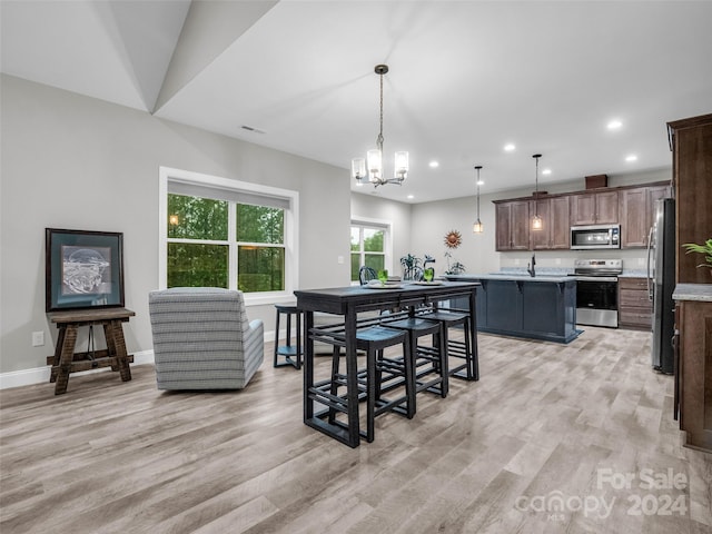 interior space featuring a center island, hanging light fixtures, light wood-type flooring, and stainless steel appliances