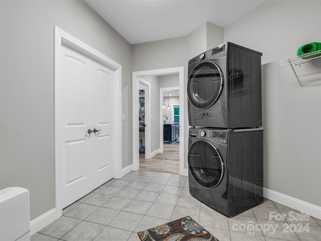 laundry room featuring stacked washer / dryer and light hardwood / wood-style floors