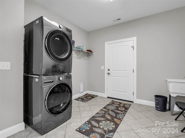 laundry room with stacked washer and clothes dryer and light tile floors