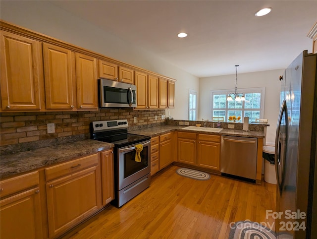 kitchen with light hardwood / wood-style flooring, kitchen peninsula, stainless steel appliances, a notable chandelier, and hanging light fixtures