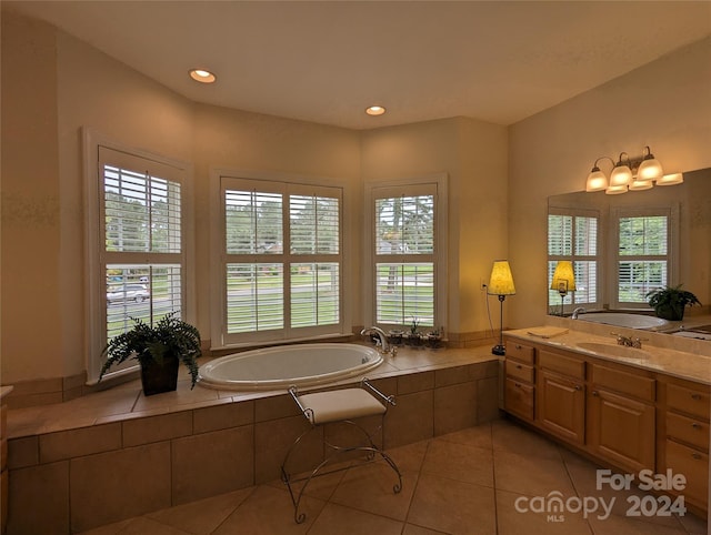 bathroom with a wealth of natural light, tiled bath, vanity, and tile floors