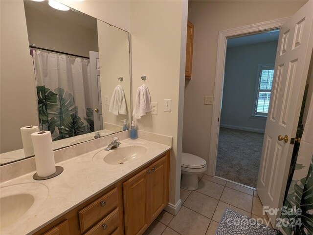 bathroom with tile floors, double sink vanity, and toilet