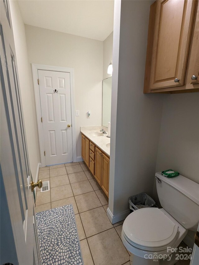 bathroom featuring tile floors, dual vanity, and toilet