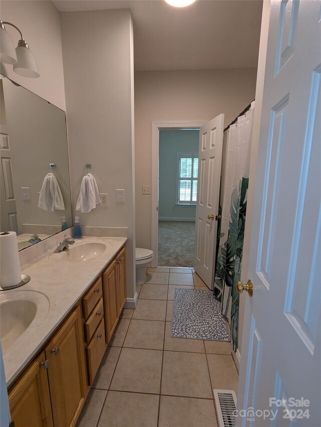 bathroom with double vanity, toilet, and tile floors