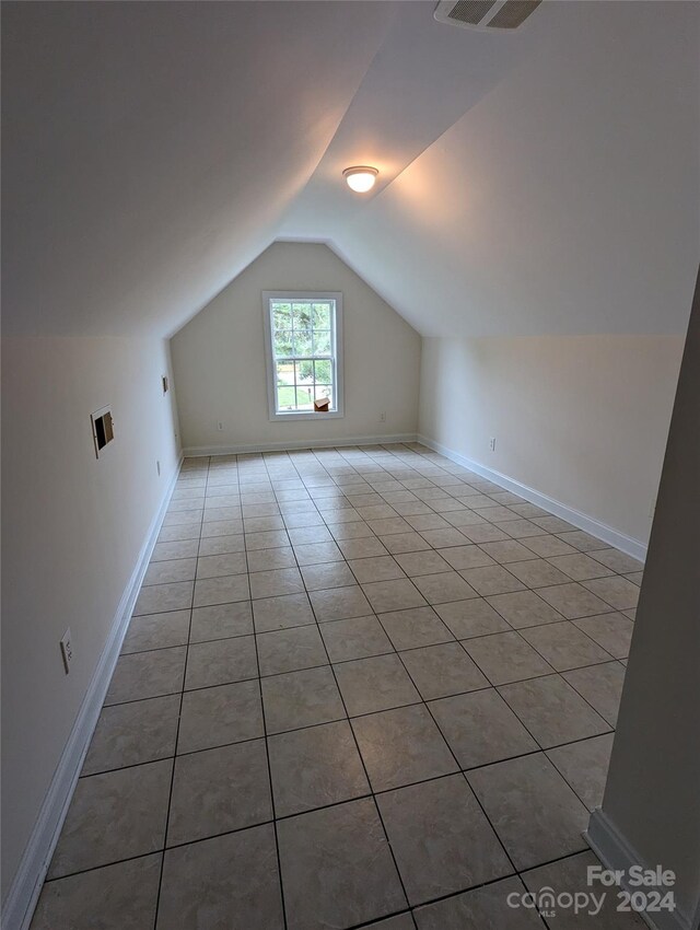 bonus room featuring tile flooring and vaulted ceiling