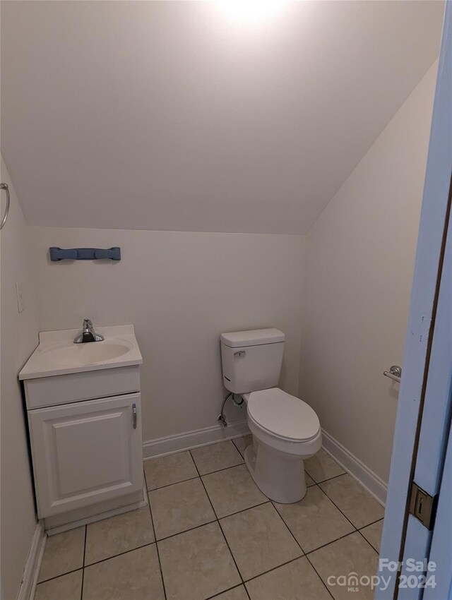 bathroom featuring tile flooring, lofted ceiling, vanity, and toilet