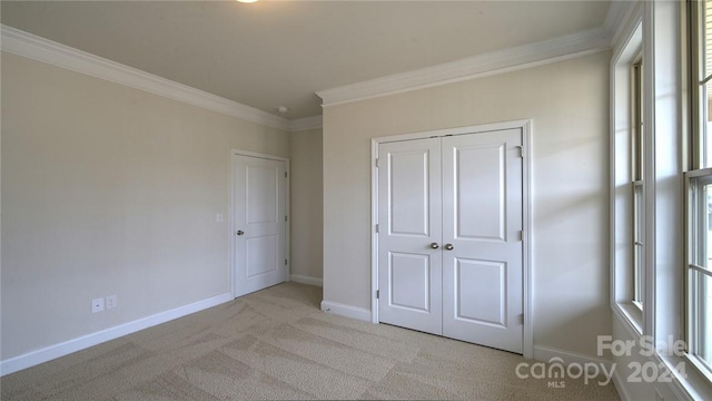 unfurnished bedroom featuring light carpet, ornamental molding, and a closet