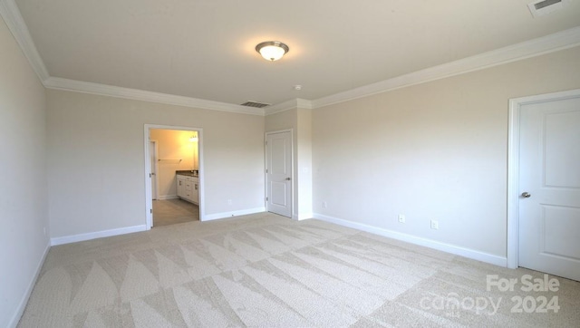 unfurnished bedroom featuring ornamental molding, ensuite bathroom, and light colored carpet