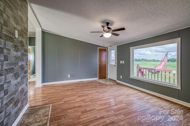 spare room featuring a textured ceiling, light wood-type flooring, a wealth of natural light, and ceiling fan