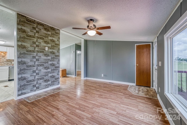 spare room with light hardwood / wood-style floors, ceiling fan, and a textured ceiling