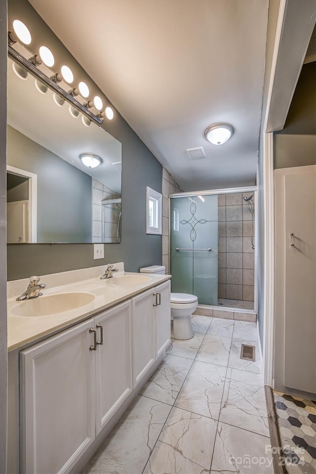 bathroom with dual sinks, oversized vanity, a shower with shower door, tile floors, and toilet