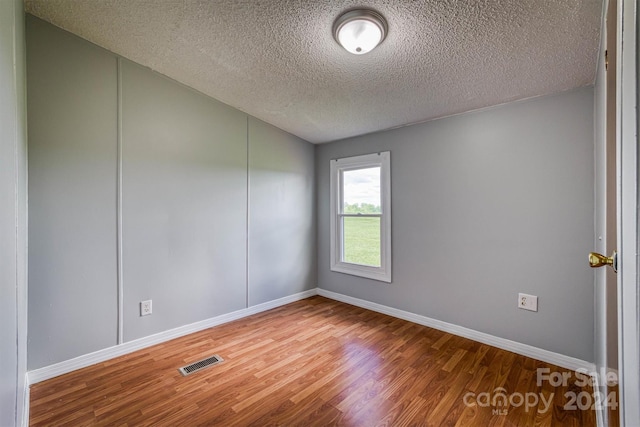 empty room featuring a textured ceiling and hardwood / wood-style floors