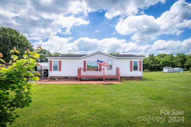 back of property with a storage unit, a deck, and a lawn