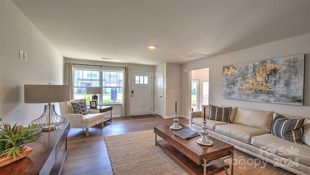 living room with a wealth of natural light and dark wood-type flooring