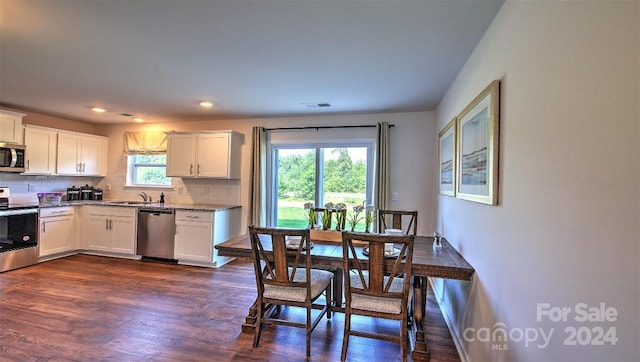 kitchen with light stone countertops, appliances with stainless steel finishes, white cabinets, dark hardwood / wood-style floors, and tasteful backsplash