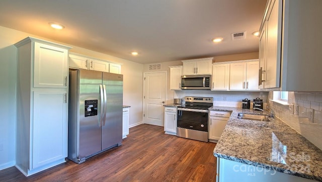 kitchen with dark hardwood / wood-style floors, tasteful backsplash, stainless steel appliances, stone counters, and white cabinetry