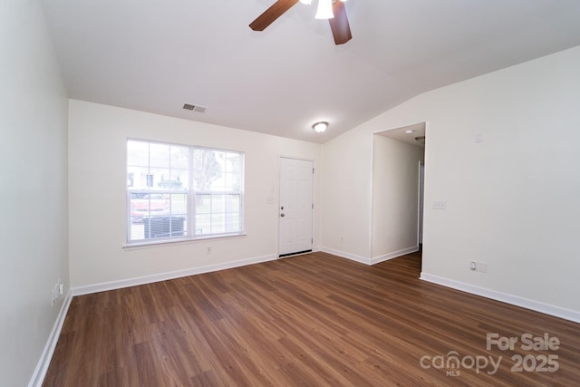 spare room with dark wood-type flooring, vaulted ceiling, and ceiling fan