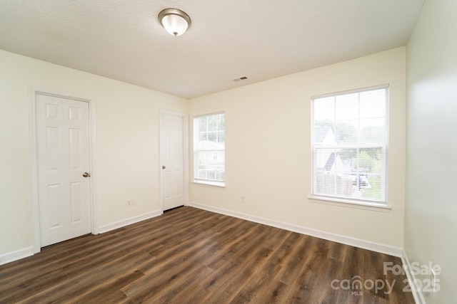 unfurnished room with dark hardwood / wood-style floors and a textured ceiling