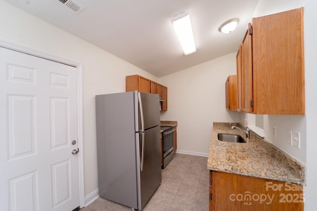 kitchen with light stone counters, appliances with stainless steel finishes, sink, and light tile patterned floors