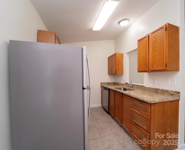 kitchen featuring light stone counters, stainless steel appliances, and sink