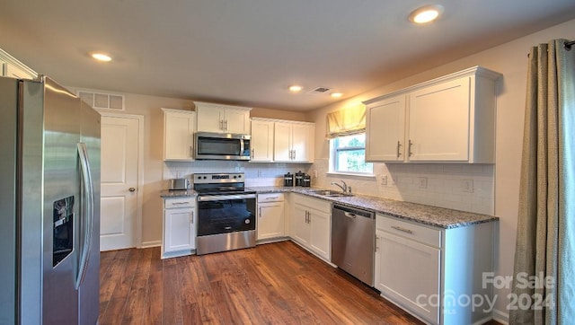 kitchen with light stone countertops, tasteful backsplash, dark wood-type flooring, white cabinetry, and appliances with stainless steel finishes