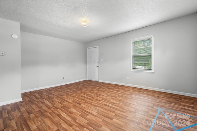 unfurnished room featuring hardwood / wood-style flooring and a textured ceiling