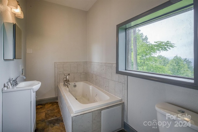 bathroom featuring tiled bath, toilet, and vanity