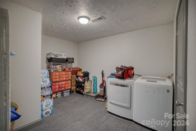 clothes washing area with a textured ceiling and washer and clothes dryer