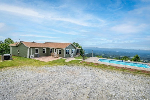 rear view of property featuring a mountain view, a fenced in pool, a patio area, and a yard