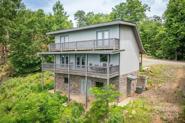 rear view of property with a balcony, cooling unit, french doors, and a patio