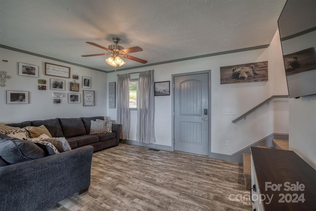 living room with ceiling fan, a textured ceiling, light hardwood / wood-style flooring, and crown molding