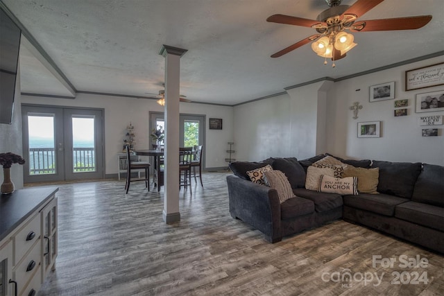 living room with a textured ceiling, hardwood / wood-style floors, french doors, ornamental molding, and ceiling fan