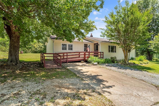 ranch-style home with a deck and a front lawn