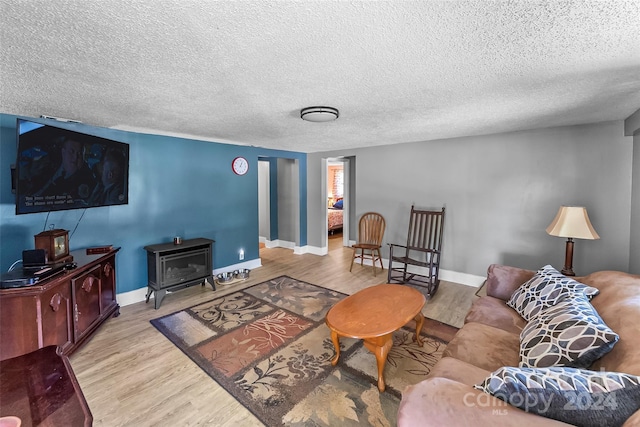 living room with wood-type flooring, a wood stove, and a textured ceiling