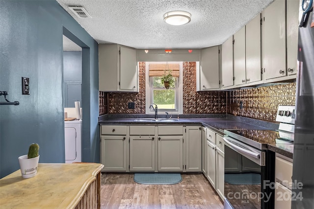 kitchen featuring light wood-type flooring, gray cabinets, range with electric cooktop, sink, and tasteful backsplash