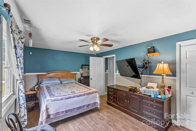 bedroom with ceiling fan, a textured ceiling, and wood-type flooring