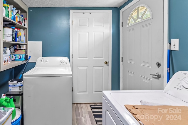 laundry area featuring independent washer and dryer, a textured ceiling, and light wood-type flooring